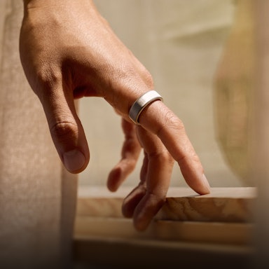 Close up of a person's hand with a Brushed Silver Oura Ring 4 on their finger